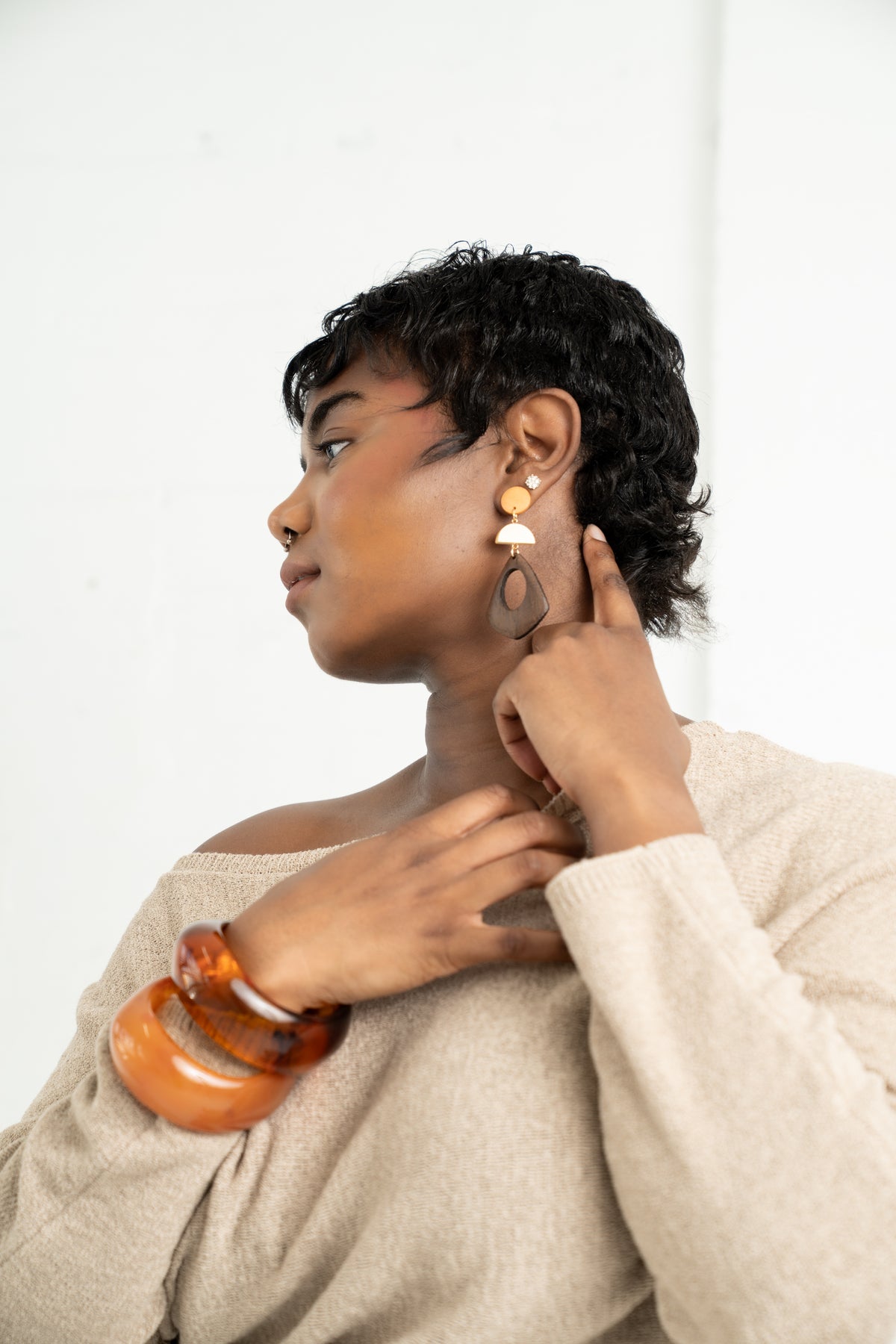 Woman wearing earrings and a bracelet against a white background
