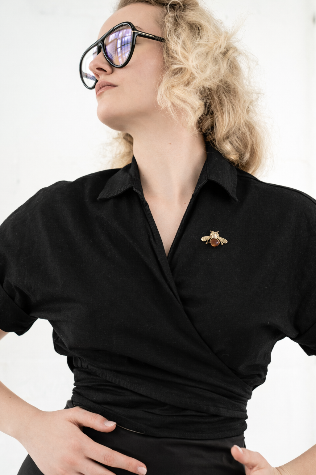 Person wearing a black shirt with a brooch on a white background