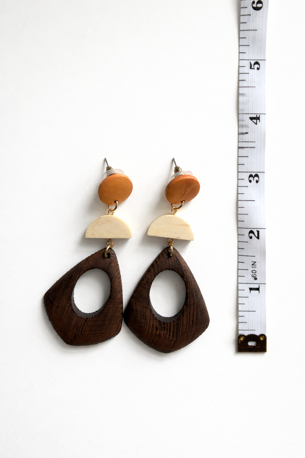Wooden earrings with a white background and a ruler for scale.