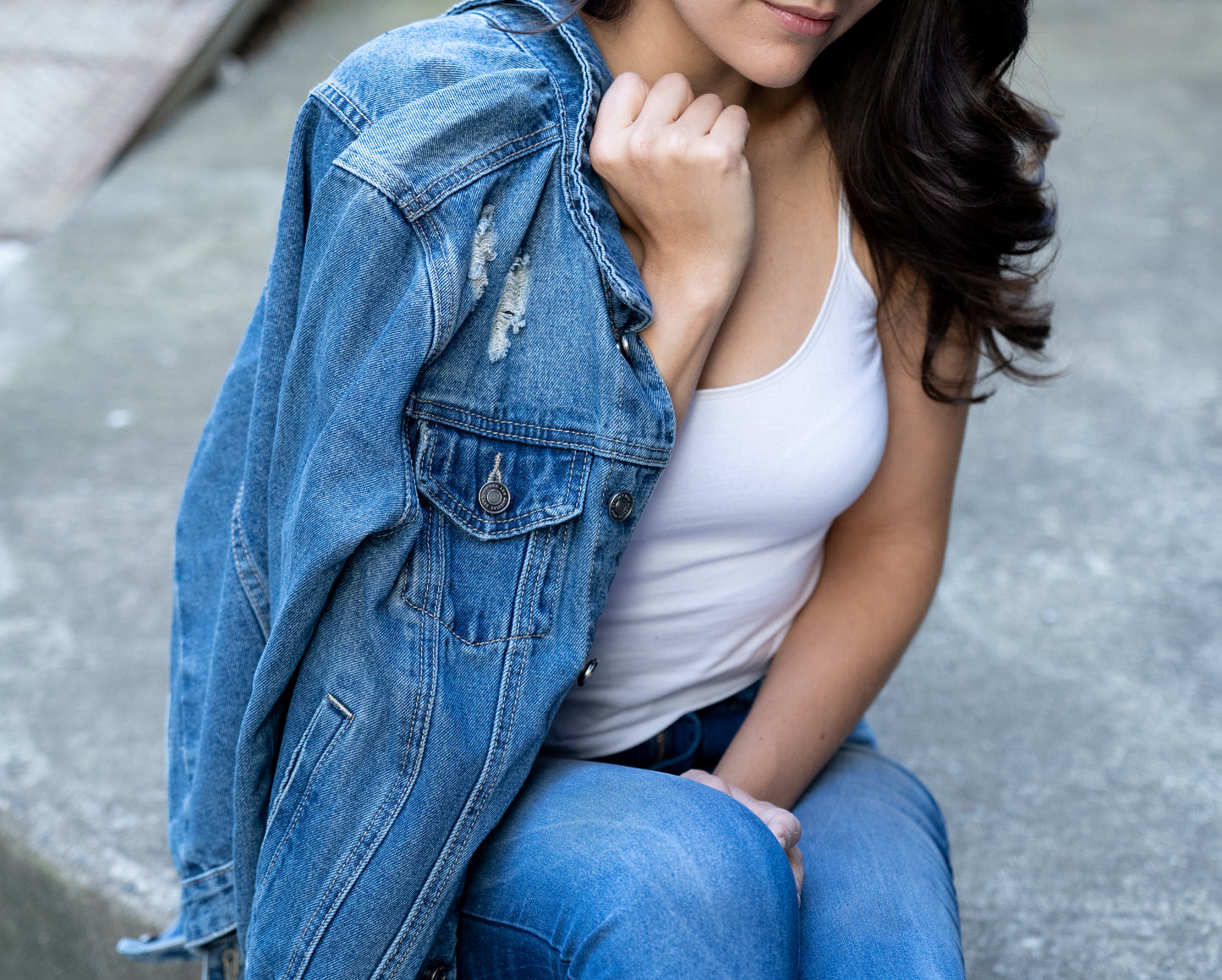 model holding Distressed Denim Trucker Jacket over the shoulder