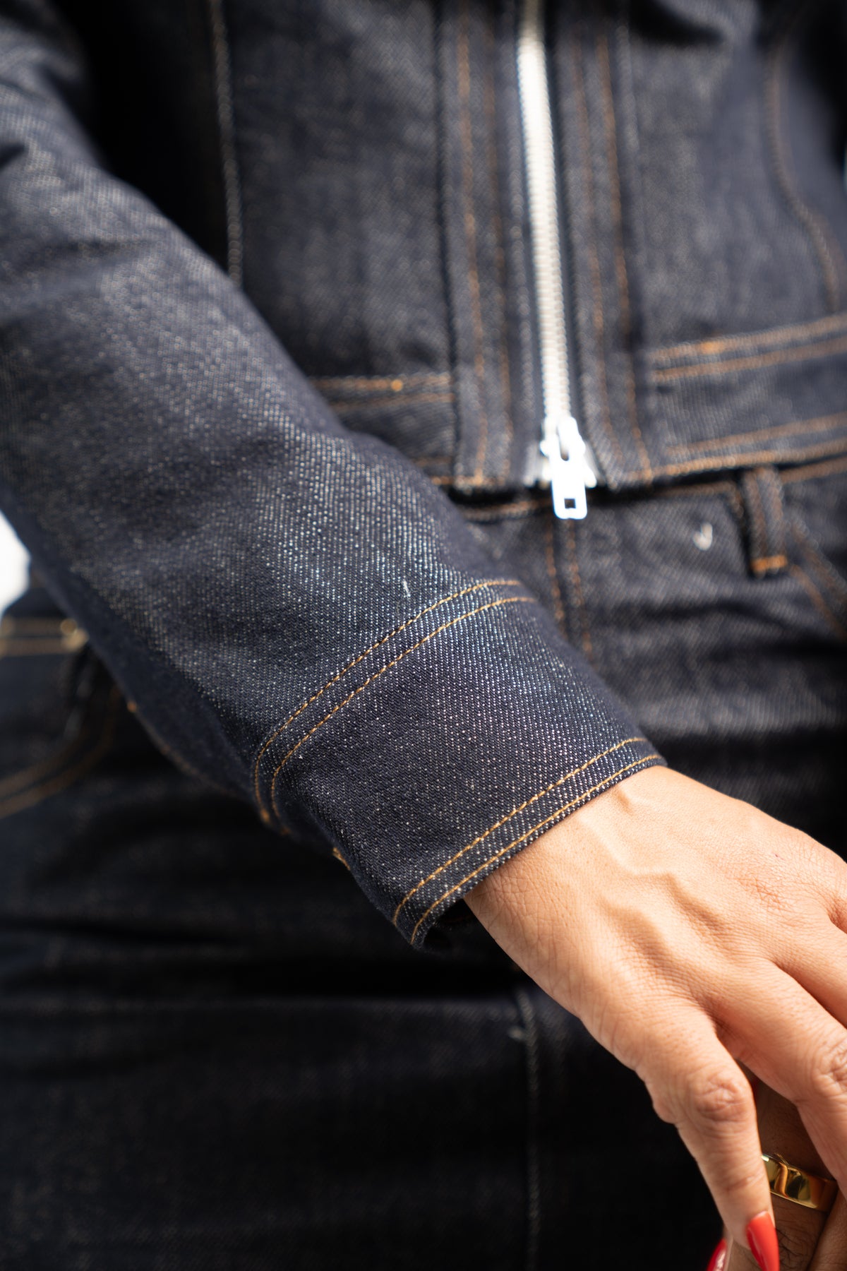 Close-up of the indigo denim jacket zipper, chest pockets and contrast stitching