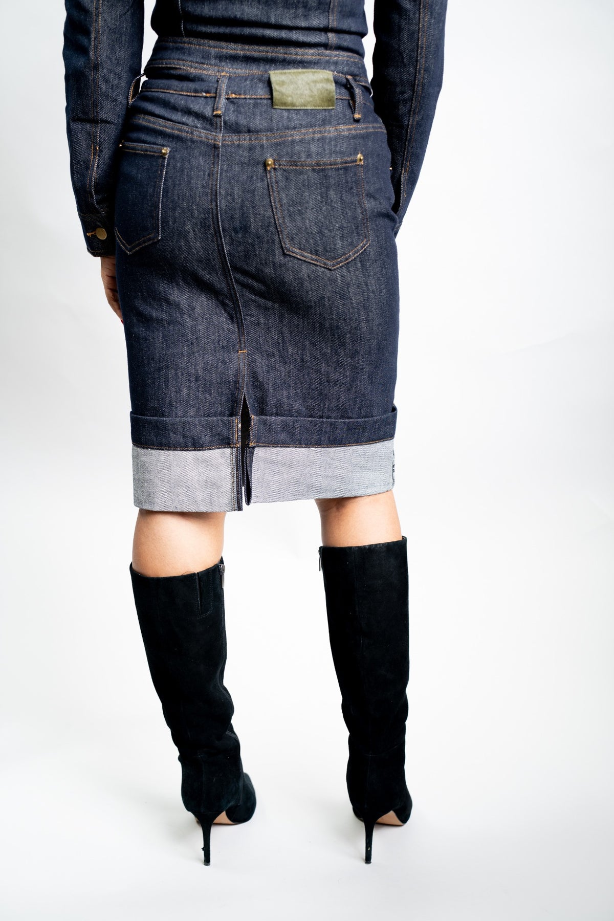 Side view of the straight indigo denim pencil skirt and statement folded cuff