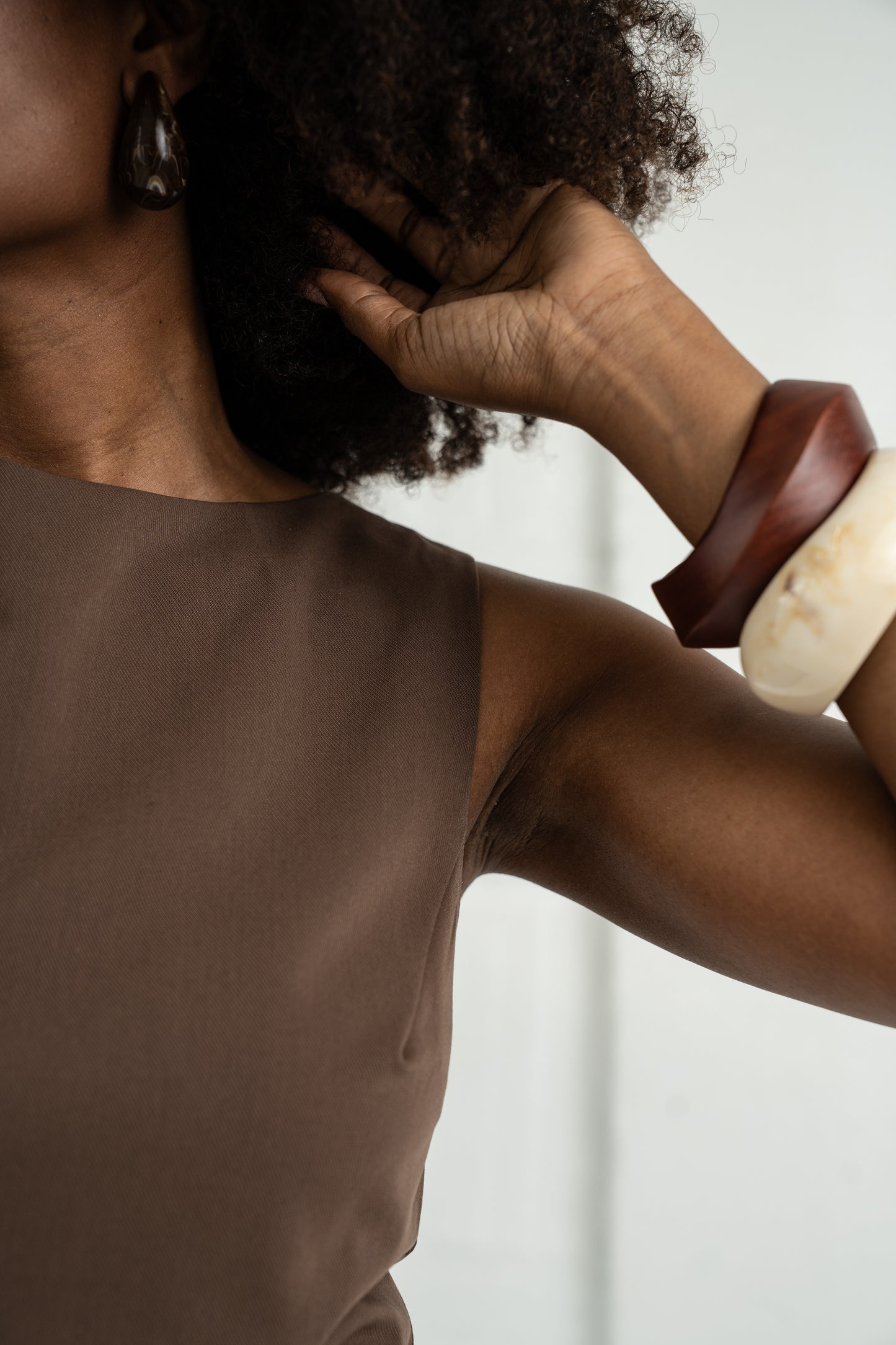 Person wearing a brown top with a plain background