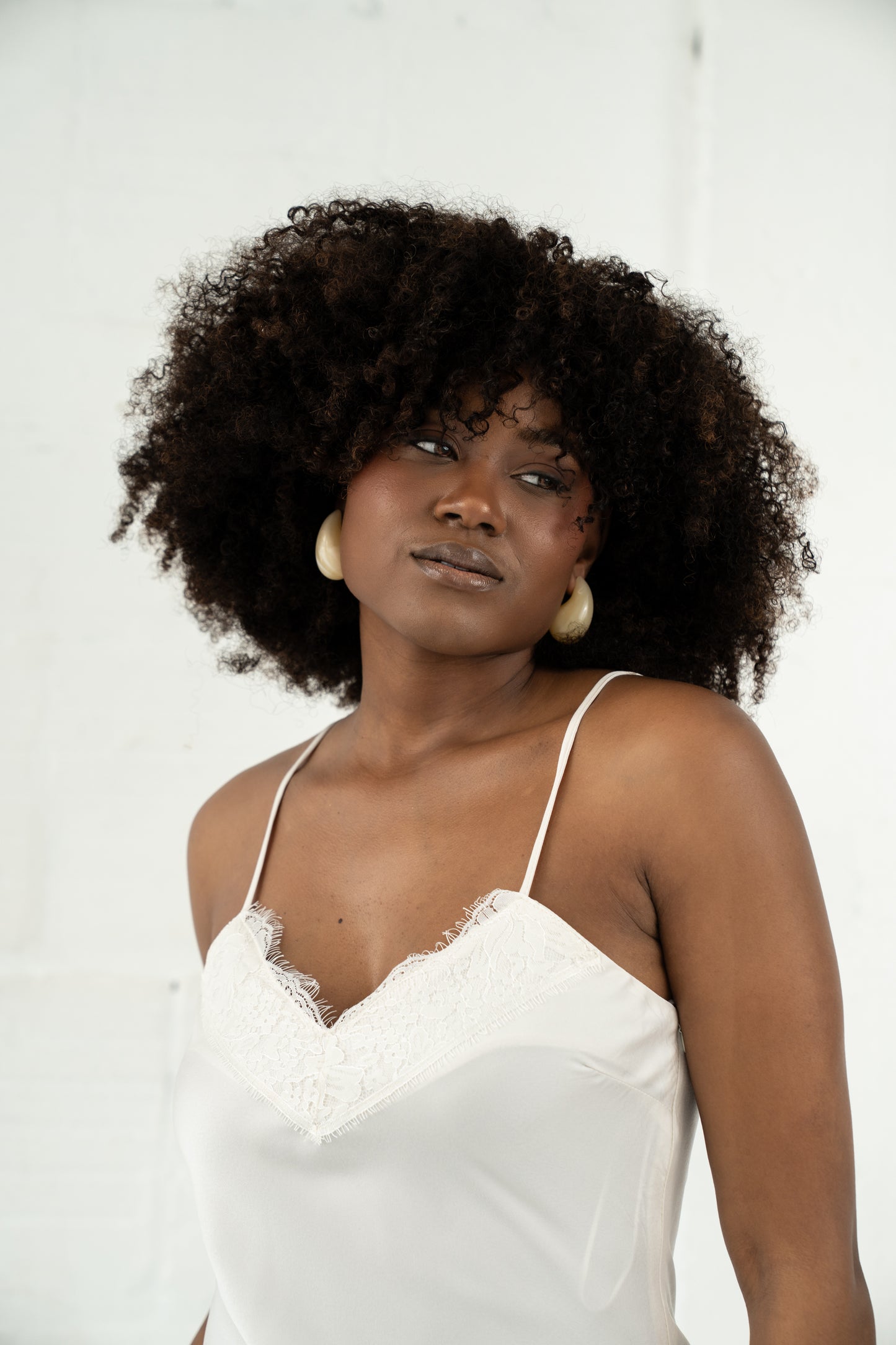 Woman wearing a white lace top against a plain background