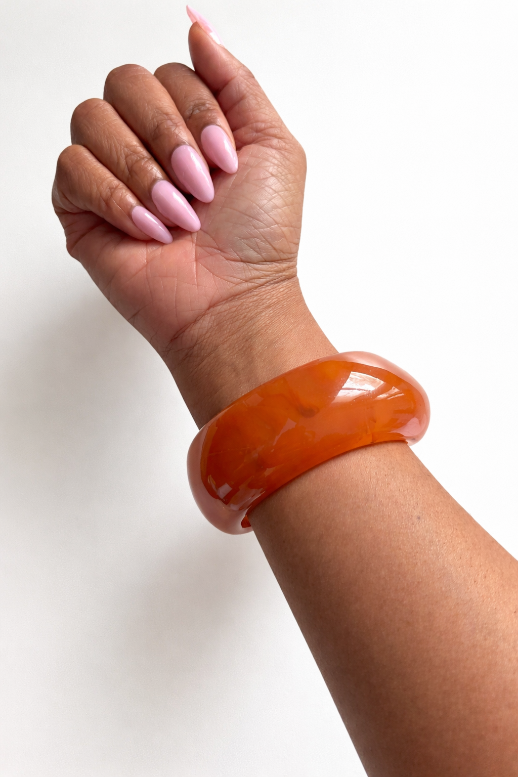 Hand wearing an orange bangle on a white background