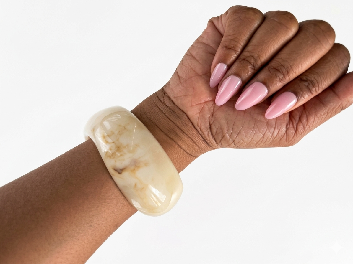 Hand wearing a large beige bracelet with a white background