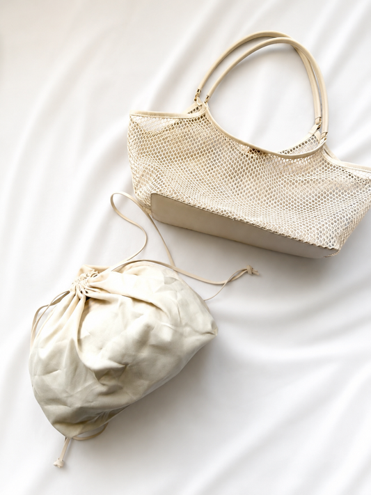 Beige handbag and drawstring bag on a white fabric background
