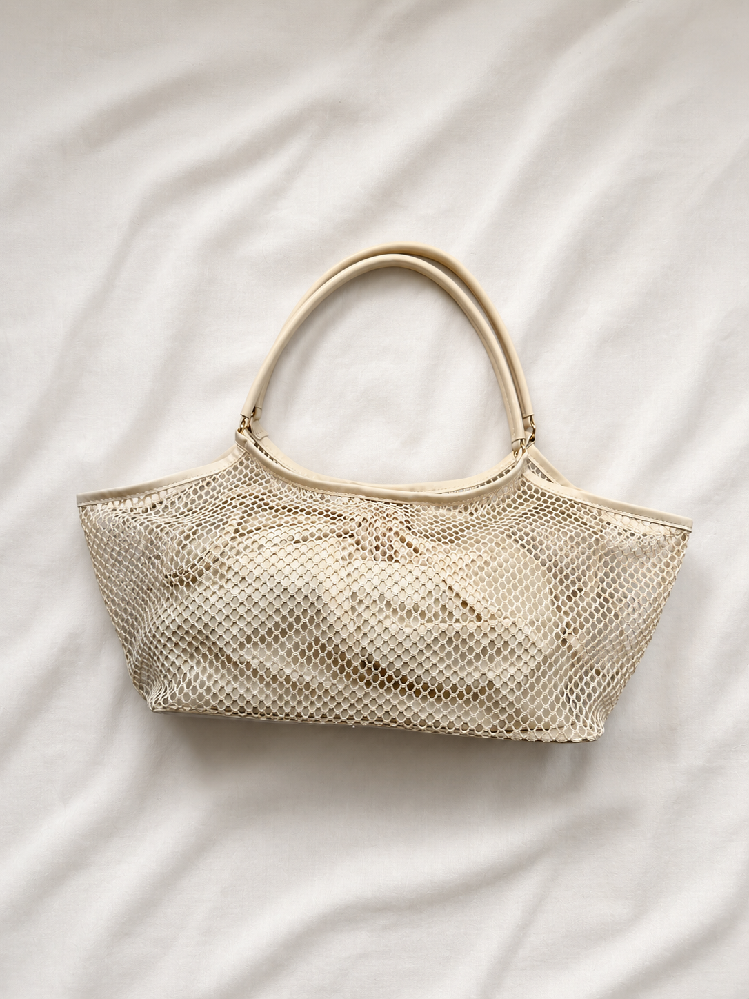 Beige mesh handbag on a white fabric background