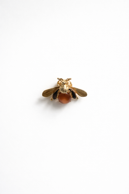 Gold bee-shaped brooch on a white background