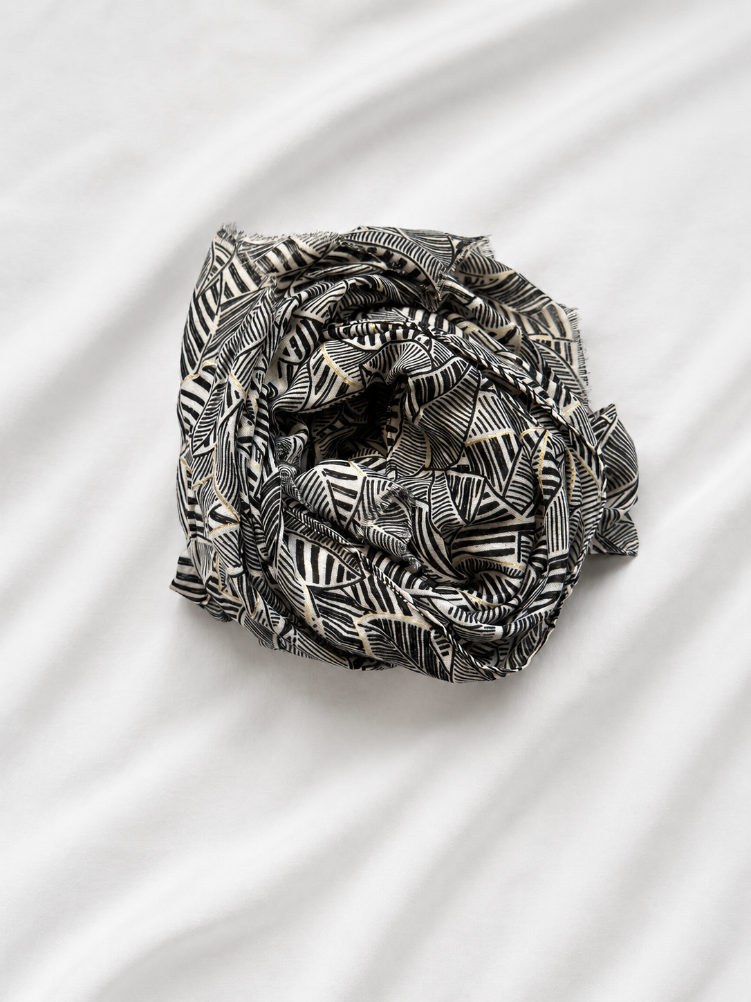 Black and white patterned scarf folded into a knot on a white fabric background