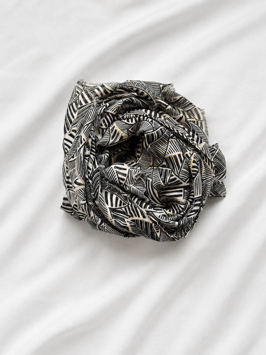 Black and white patterned scarf folded into a knot on a white fabric background