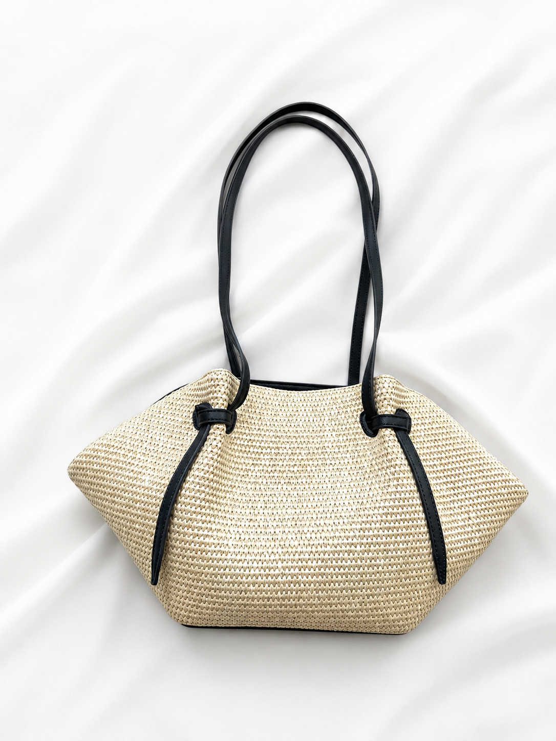 Woven handbag with black handles on a white background