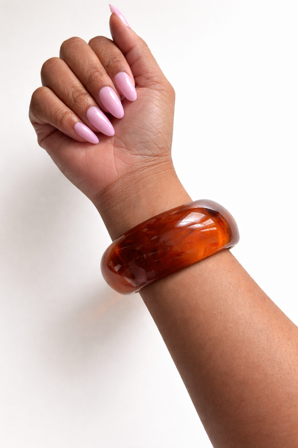Hand wearing a large brown bangle on a white background