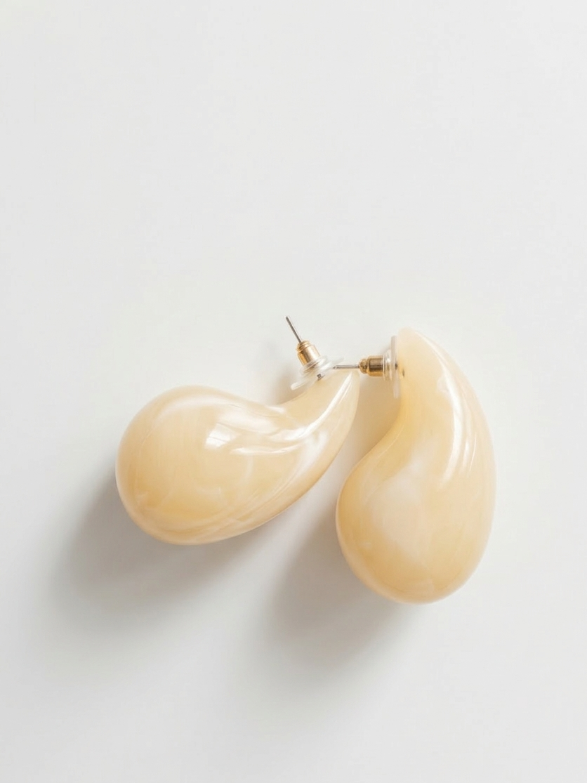 Pair of beige teardrop earrings on a light gray background