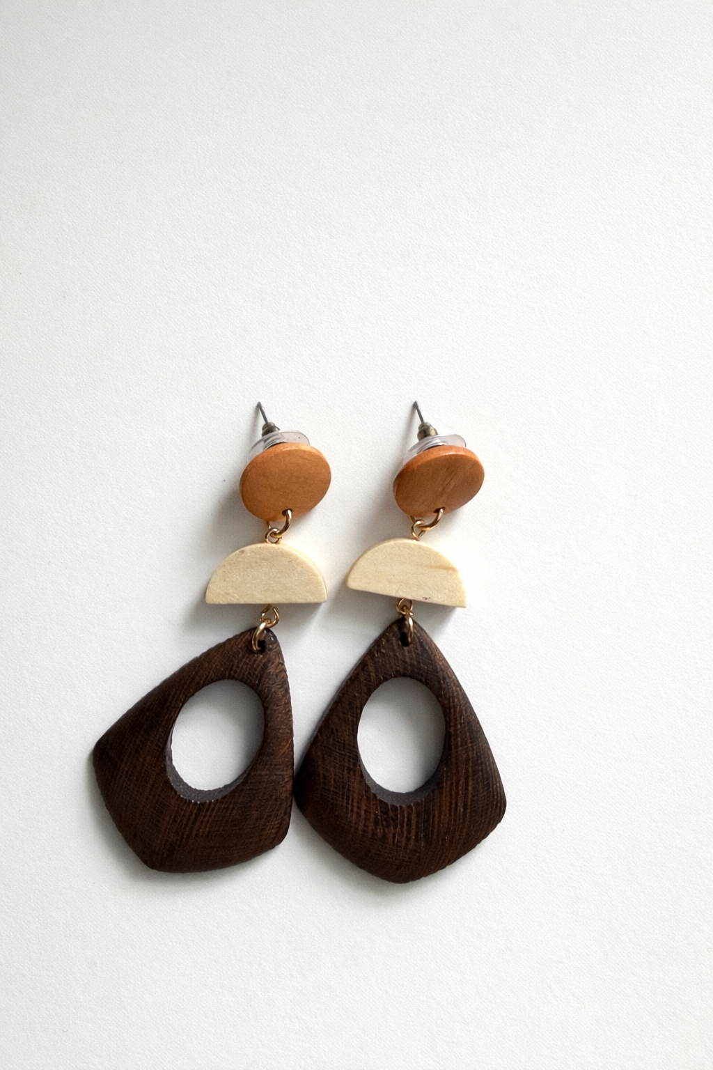 Wooden earrings with brown, beige, and white components on a white background