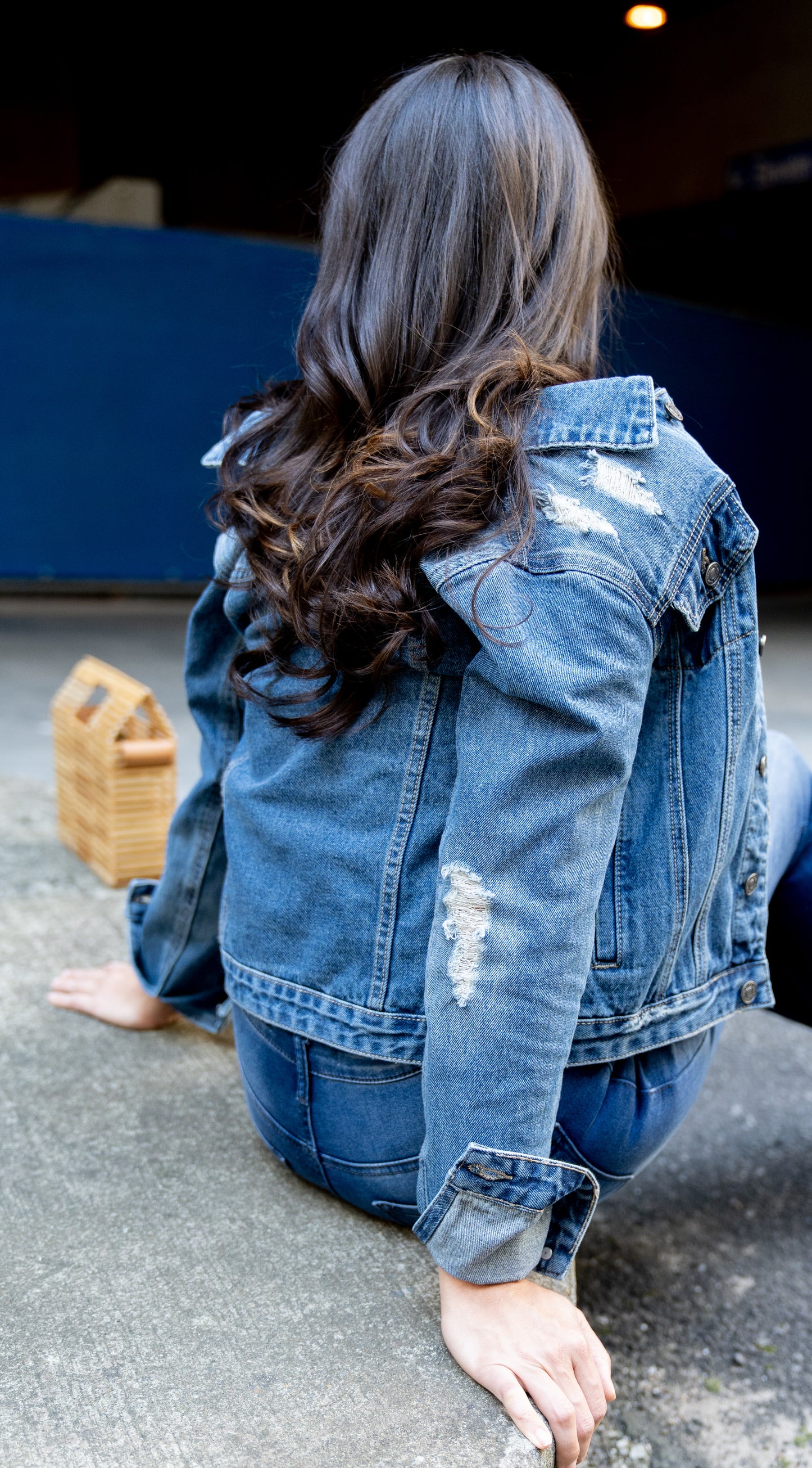 back view of model wearing Distressed Denim Trucker Jacket 